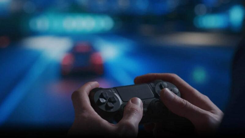 A gamer using a controller with the image of a racing game blurred in the background