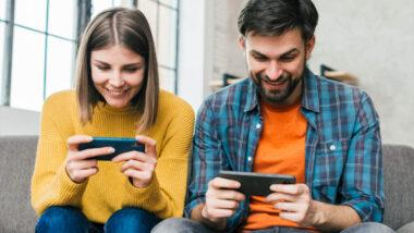 a woman and a man playing mobile games